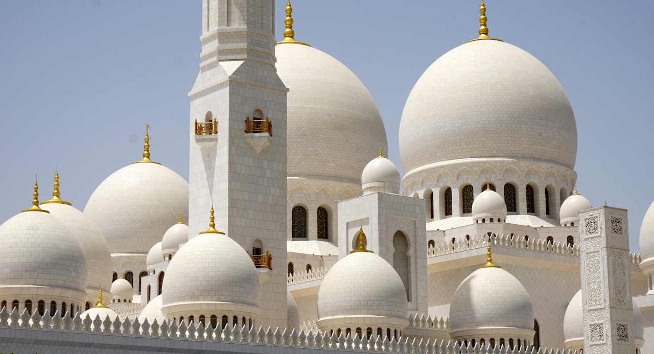 A stunning view of the domes and minarets of Sheikh Zayed Grand Mosque under a clear sky.